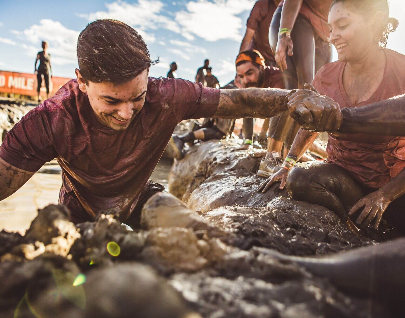 Participant holding the hand of his teammate to get into the land from the mud